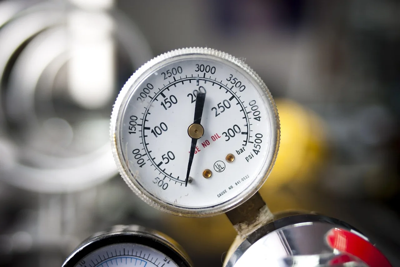 Mechanic and driver checking a sedan with the hood open and a low oil pressure gauge concern