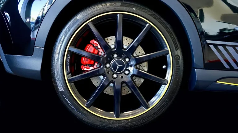 Mechanic inspecting a car wheel and brake caliper in a sunlit garage