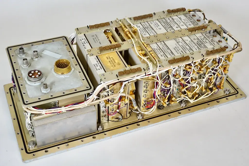 Automotive technician inspecting a transmission control module beside an open hood