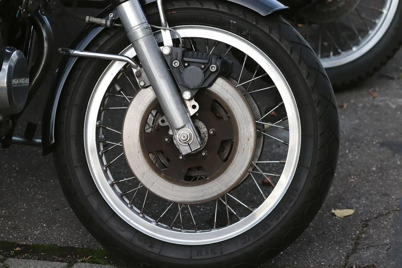 Mechanic inspecting an exposed brake rotor and caliper on a sedan in a repair bay