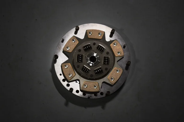 Mechanic checking a car's clutch system in a garage while the clutch pedal is pressed