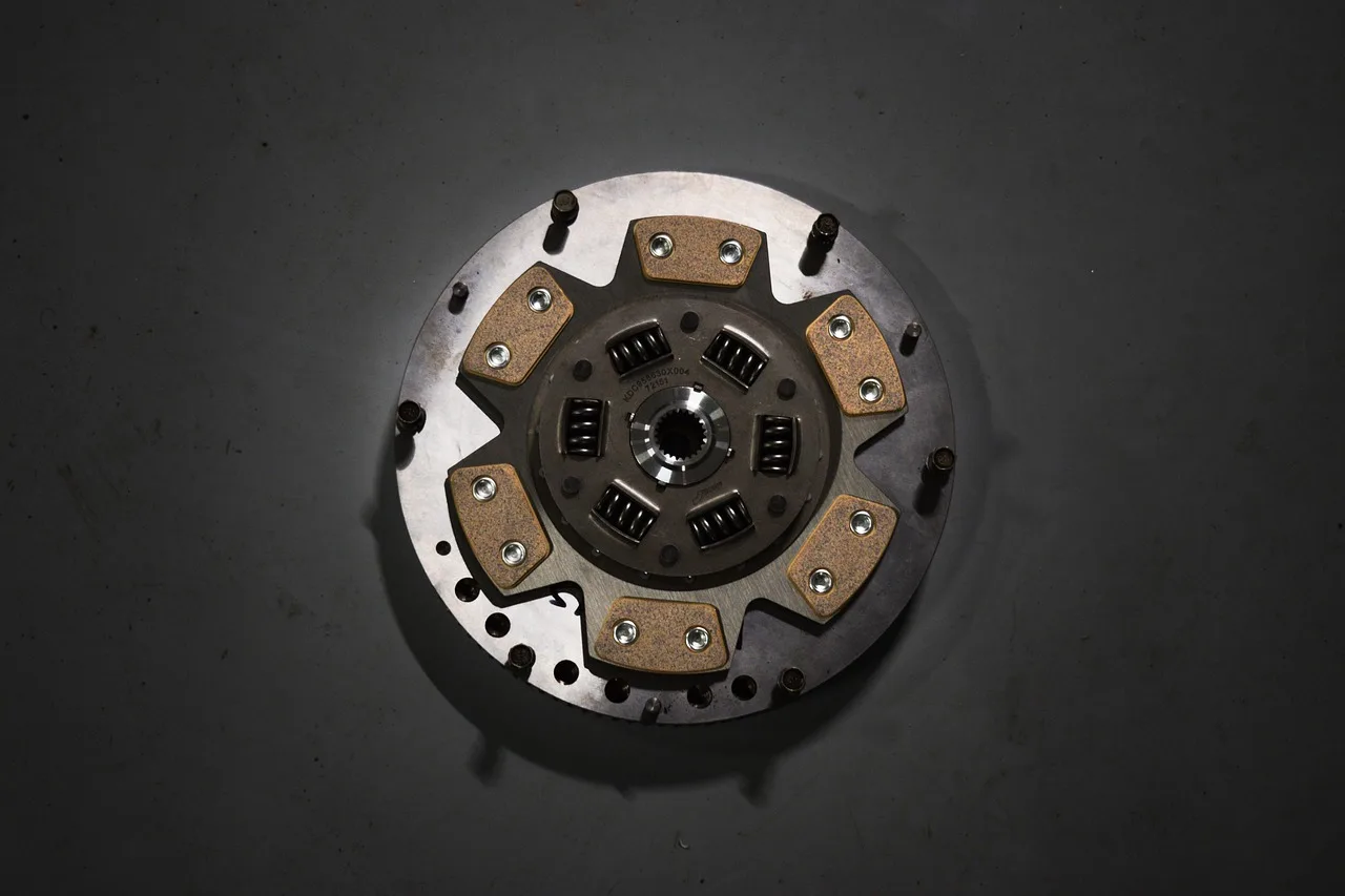 Mechanic checking a car's clutch system in a garage while the clutch pedal is pressed