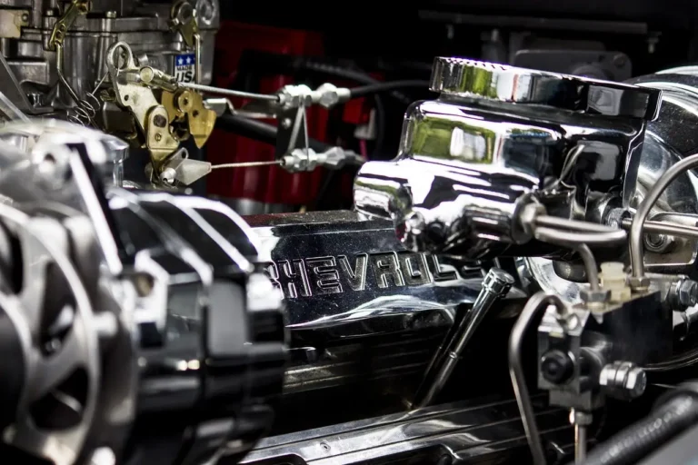 Car engine bay with the hood open, showing the engine block, belts, hoses, and air intake