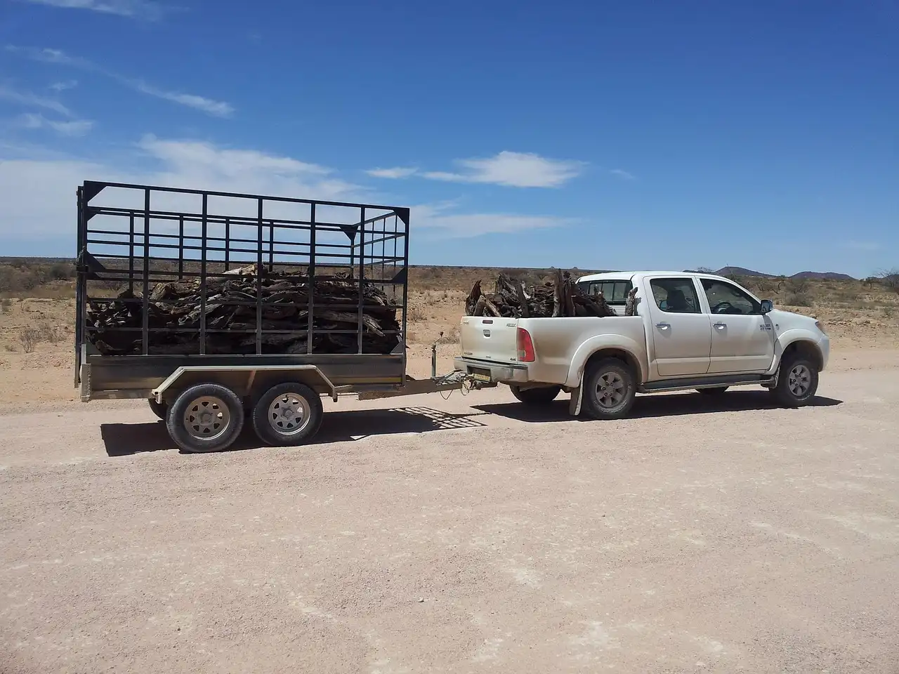 A midsize SUV towing a small utility trailer with gear loaded in a suburban driveway.