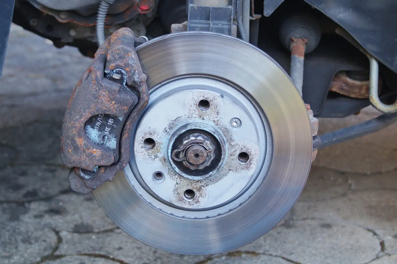 Mechanic pressing a brake pedal in a sedan during a brake pedal sink diagnosis.
