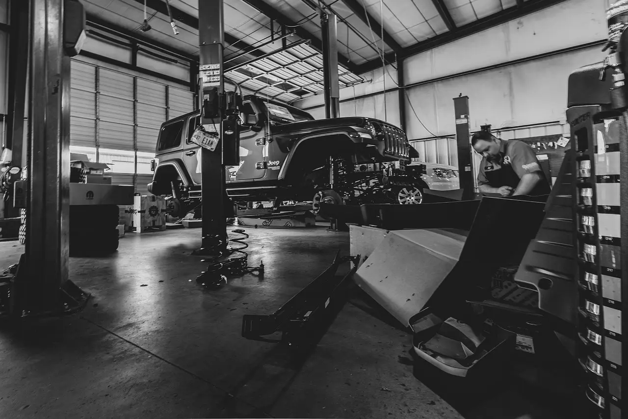 Mechanic inspecting a car on a lift for a rattling noise over bumps