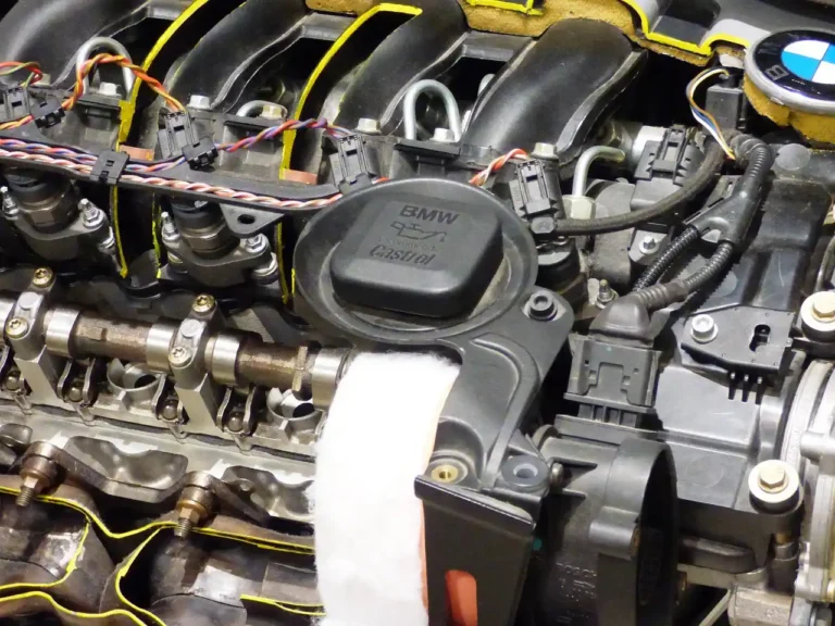 Mechanic inspecting foamy engine oil on a dipstick in an open engine bay