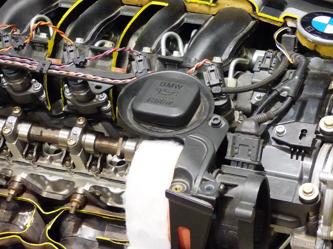 Mechanic inspecting foamy engine oil on a dipstick in an open engine bay